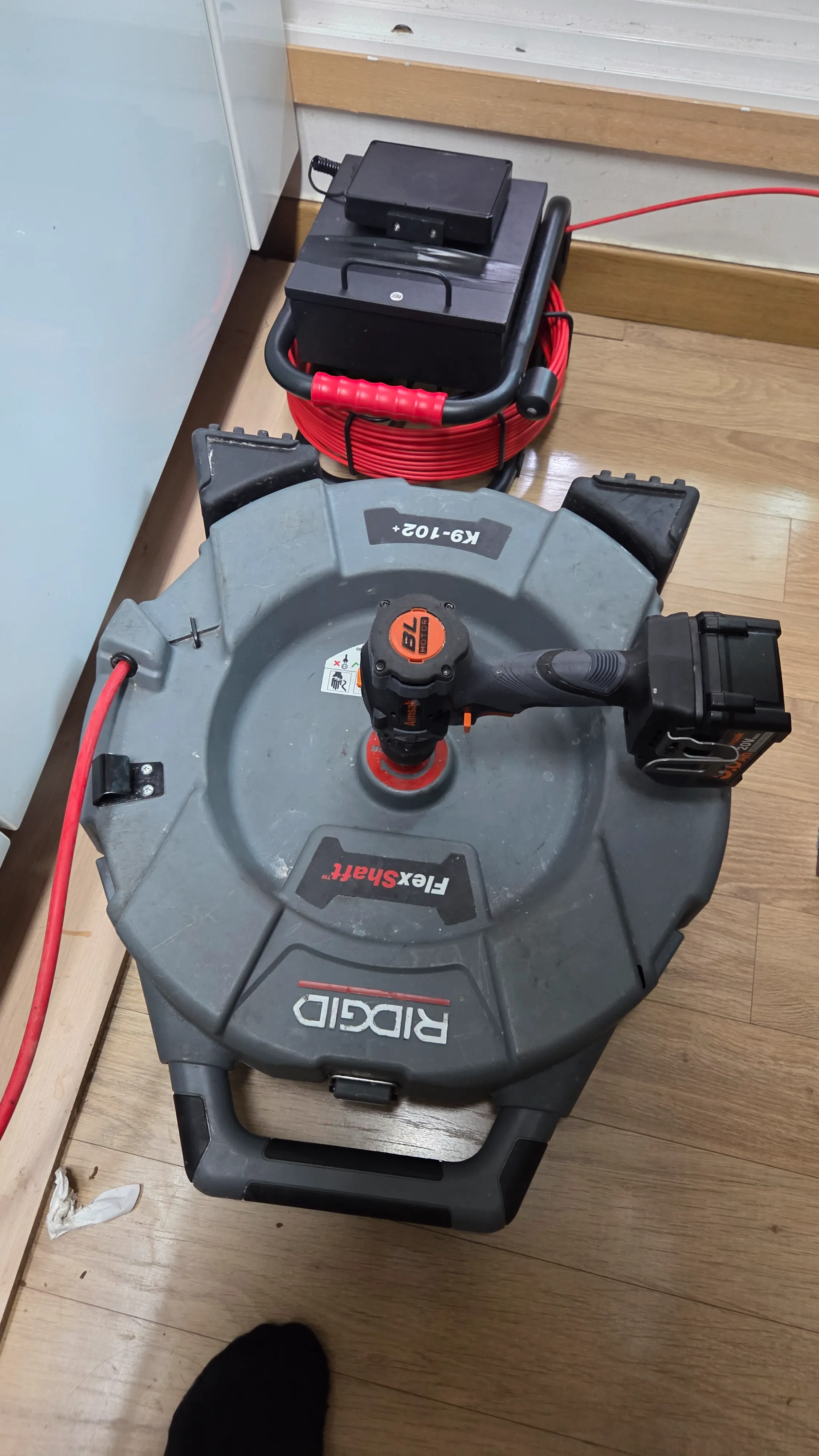 RIDGID K9-102+ 플렉스 샤프트 장비를 가동하여 막힌 주방 하수구 기름때를 분쇄하는 모습